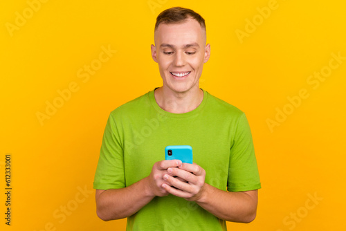 Photo of attractive guy in casual outfit holding smart phone online shopping over yellow background