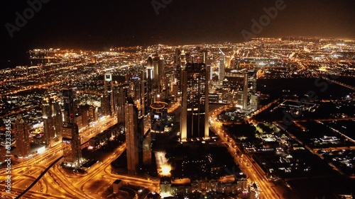 Panorama de la ville de Dubai de nuit pris depuis le sommet du Burj Khalifa, plus haut immeuble du monde. On y voit les autoroute, les routes, les échangeurs, les lumières, les autres buildings.