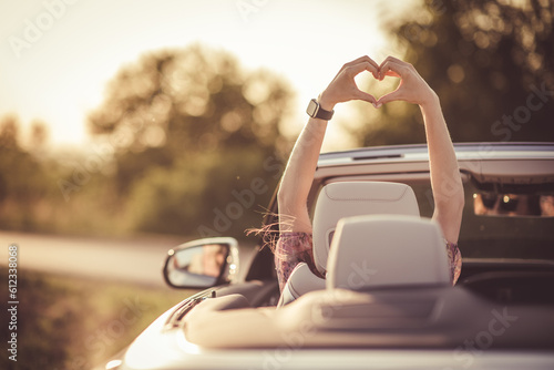 Love gesture in a convertible. Happy woman during sunset in her car.