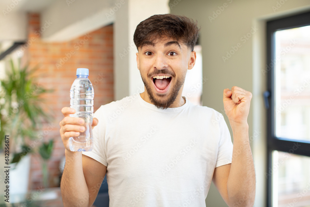 young handsome man feeling shocked,laughing and celebrating success. water bottle concept young handsome man feeling shocked,laughing and celebrating success. water bottle concept