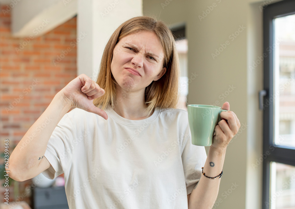 young pretty woman feeling cross,showing thumbs down. coffee cup concept young pretty woman feeling cross,showing thumbs down. coffee cup concept