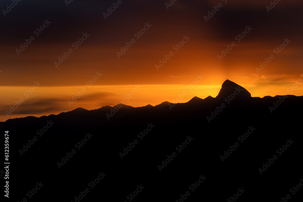 Majestic Mountain Peak Silhouette at Sunset with Vibrant Orange Sky