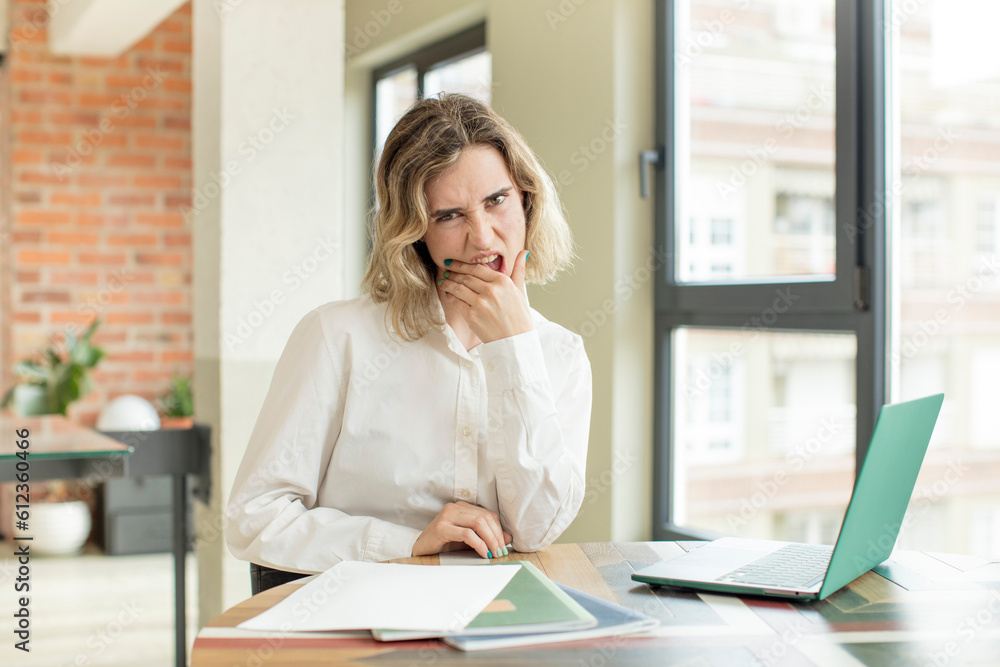 pretty woman with mouth and eyes wide open and hand on chin. home work telecommuting concept pretty woman with mouth and eyes wide open and hand on chin. home work telecommuting concept