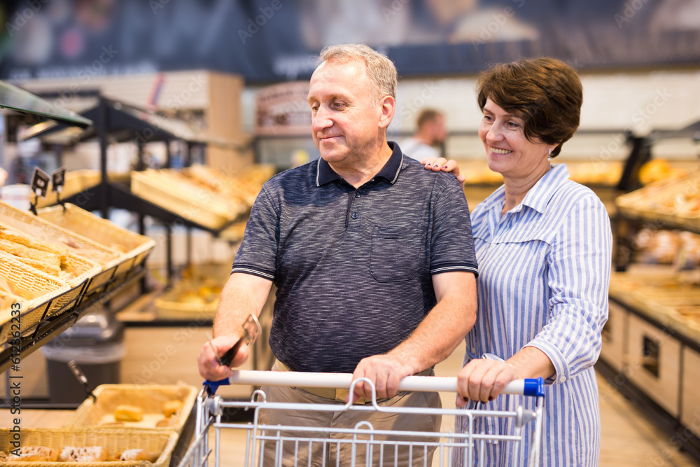 Mature couple husband and wife choose bakery products in the grocery section in supermarket