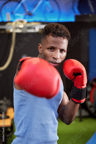 Powerful Black Male Boxer Throwing a Punch with Gloves, Demonstrating Strength and Skill in the Ring © JoseIMartin