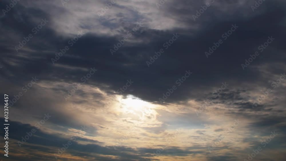 A small dawn sun barely shines through dark clouds. Dark sky at sunrise. A small dawn sun barely shines through dark clouds. Dark sky at sunrise.