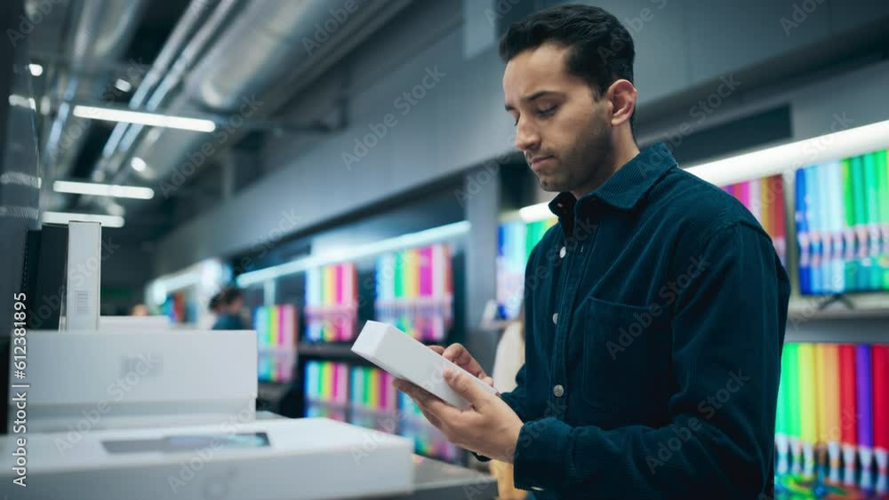 Portrait of a Stylish Hispanic Man Looking at a Box with Modern Smartphone, Reading Model's Specifications and Features. Client Shopping for a New Mobile Phone in a Home Electronics Store