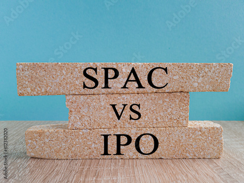 SPAC vs IPO symbol. Blocks with words 'SPAC, special purpose acquisition company' and 'IPO, initial public offering' on blue background, wooden table. Copy space. Business and SPAC vs IPO concept. photo