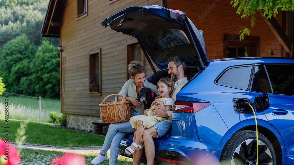 © Halfpoint - Happy family sitting in a car trunk and waiting for charging.