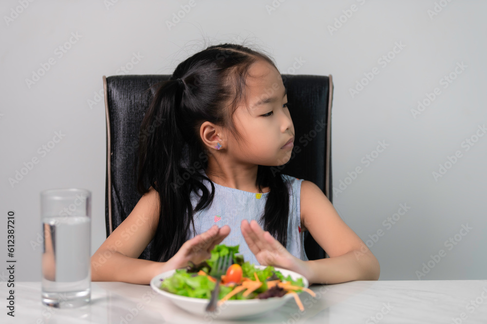 Little asian cute girl refuses to eat healthy vegetables.Nutrition & healthy eating habits for kids concept.Children do not like to eat vegetables.
