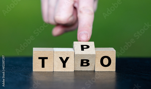 Symbol for correcting a typo. Hand turns dice and corrects the expression tybo to typo. photo