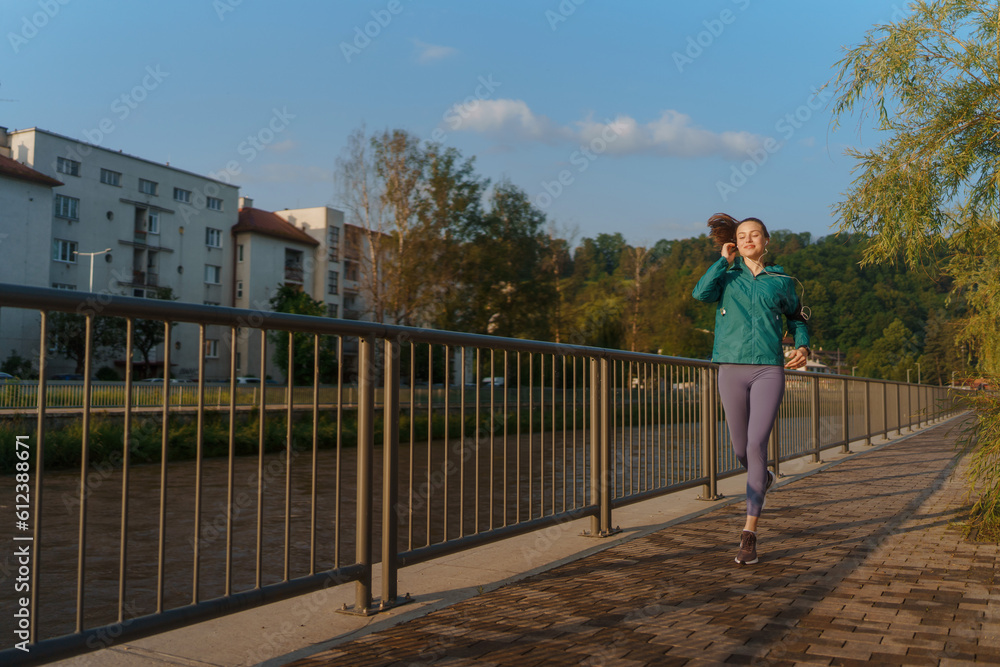 Portrait of beautiful woman runner listening music with headphones during her workout session.