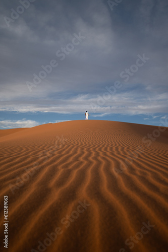 Obraz na płótnie Stunning view of a tourist walking on a sand dune in Merzouga, Morocco. w salonie