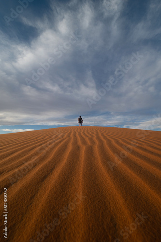 Stunning view of a tourist walking on a sand dune in Merzouga  Morocco.