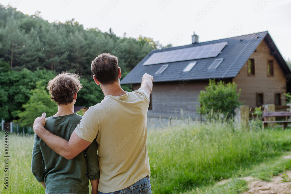 Father showing roof with solar panels to his son. Alternative energy, saving resources and sustainable lifestyle concept. Father showing roof with solar panels to his son. Alternative energy, saving resources and sustainable lifestyle concept.