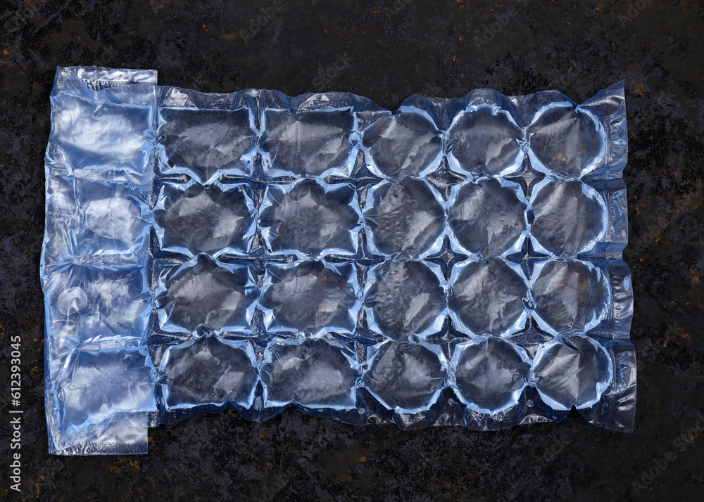 Plastic bag with water for ice on a dark background. Blue plastic ...