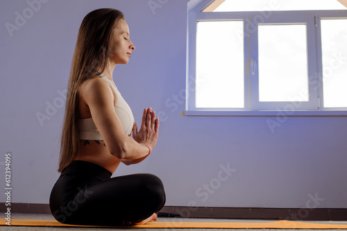 Yoga slim woman sitting on carpet and doing asana in the gym