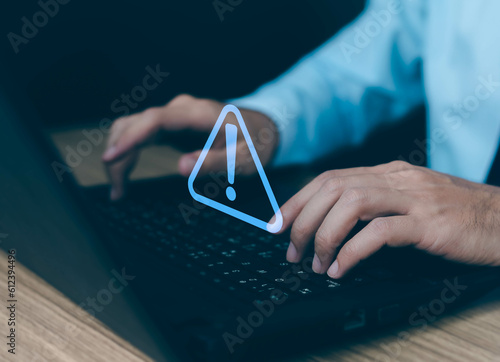 Businessman using computer laptop with triangle caution warning sing for notification error and maintenance concept.