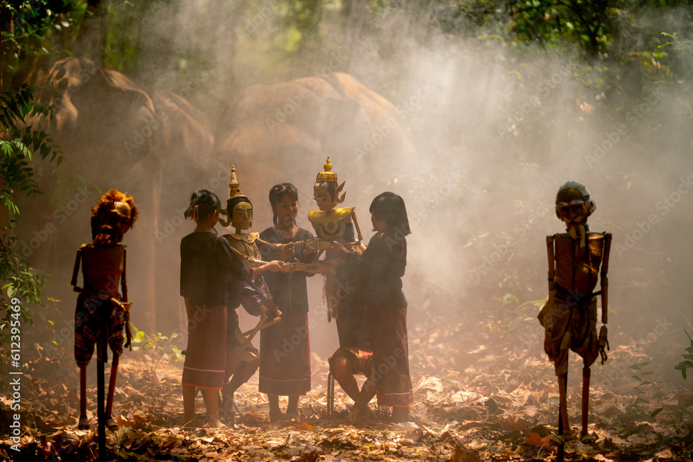 Obraz premium Group of Asian children show or practice manipulate the puppets in front of big elephant in walkway in jungle and they look happy for this traditional culture.