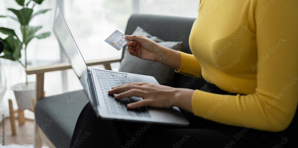 Naklejka premium Business woman, young woman holding credit card and using laptop computer for online shopping, e-commerce, banking, internet application, spending money, working from home startup business ideas