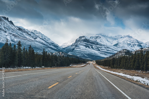 Highway road on the Icefields Parkway with rocky mountains and pine forest in winter