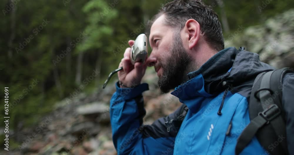 A man, close-up portrait, takes a photo of a landscape with a small camera in the mountains in rainy weather. A man, close-up portrait, takes a photo of a landscape with a small camera in the mountains in rainy weather.
