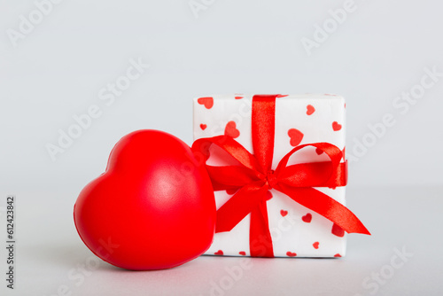 gift box with red bow and red heart on colored background. Perspective view. Flat lay