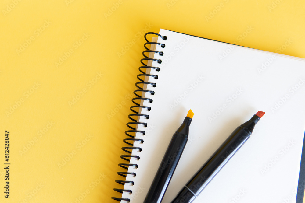 notebook and markers on the yellow background notebook and markers on the yellow background
