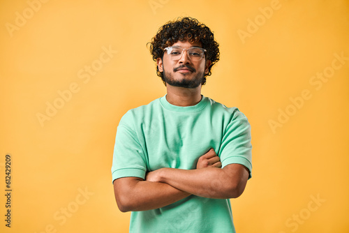 Fotografia Portrait of a handsome young man in glasses and a turquoise t-shirt with his arms crossed looking at the camera