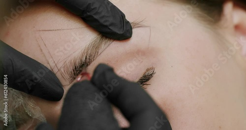 Microblading, permanent makeup tattoo close up. The master makes permanent eyebrow makeup with a needle tattoo machine. Microblading brows tattooing. Dark pigment is injected under skin. photo