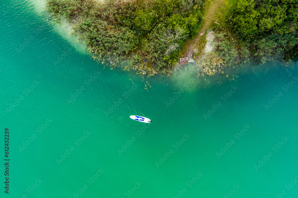 Aerial top down view of beautiful green waters of lake Gela. Birds eye view of scenic emerald lake surrounded by pine forests. Clouds reflecting in Gela lake, near Vilnius, Lithuania.