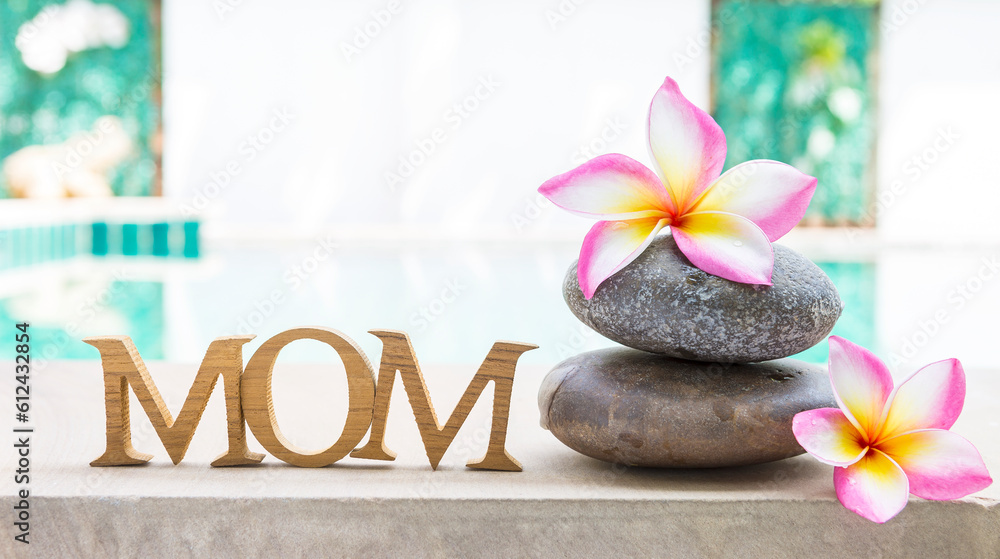 Mom wooden text with beautiful plumeria flower over blurred garden background, mother's day background idea