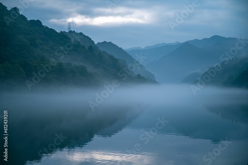 Lake with reflections and foggy mountains on the background
