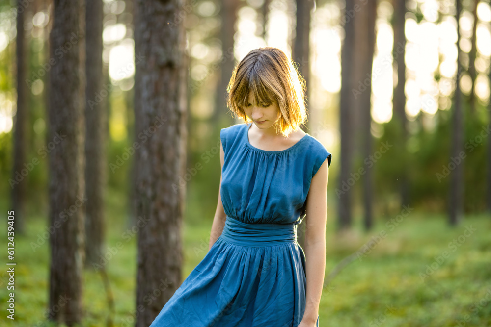 Adorable young girl having fun in a forest. Happy teenager portrait in summer park. Teen wearing blue dress. Adorable young girl having fun in a forest. Happy teenager portrait in summer park. Teen wearing blue dress.