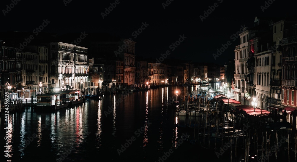 Beautiful view of buildings and canal with boats in Venice, Italy at night