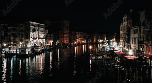 Beautiful view of buildings and canal with boats in Venice, Italy at night