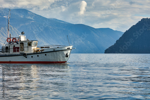 Part of a large motor boat or a boat on the lake against the backdrop of the beautiful majestic Altai Mountains. Tourist water vessel moves along a calm river in good weather