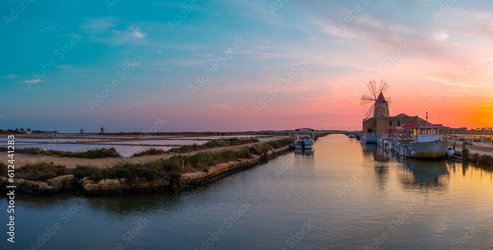 Panoramic sunset at the salt flats with the old windmill. Saline dello Stagnone. Marsala, Trapani, Sicily, Italy, Europe.