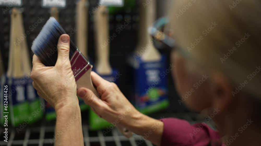 Attractive mature woman looks closely at paint brush for home remodeling project. Attractive mature woman looks closely at paint brush for home remodeling project.