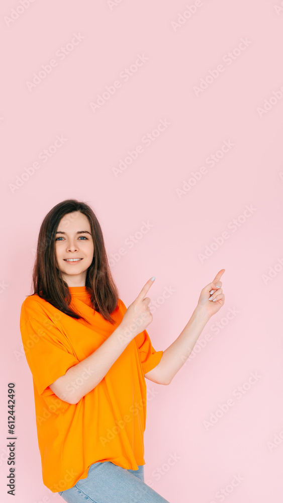 Inviting Emptiness: Cheerful Woman Pointing with Two Fingers to an Empty Space - Drawing Attention to Available Opportunities, Isolated on Pink Background. Inviting Emptiness: Cheerful Woman Pointing with Two Fingers to an Empty Space - Drawing Attention to Available Opportunities, Isolated on Pink Background.