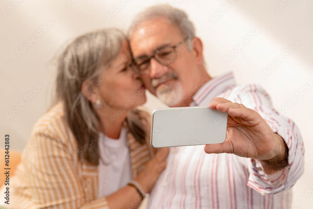 Positive european mature woman kiss to man, take selfie on smartphone, enjoy date together Positive european mature woman kiss to man, take selfie on smartphone, enjoy date together