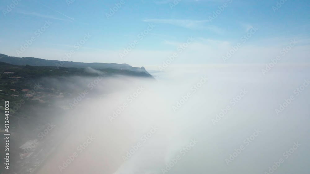 Drone shot of mountainous view behind fog under blue sunny sky Drone shot of mountainous view behind fog under blue sunny sky