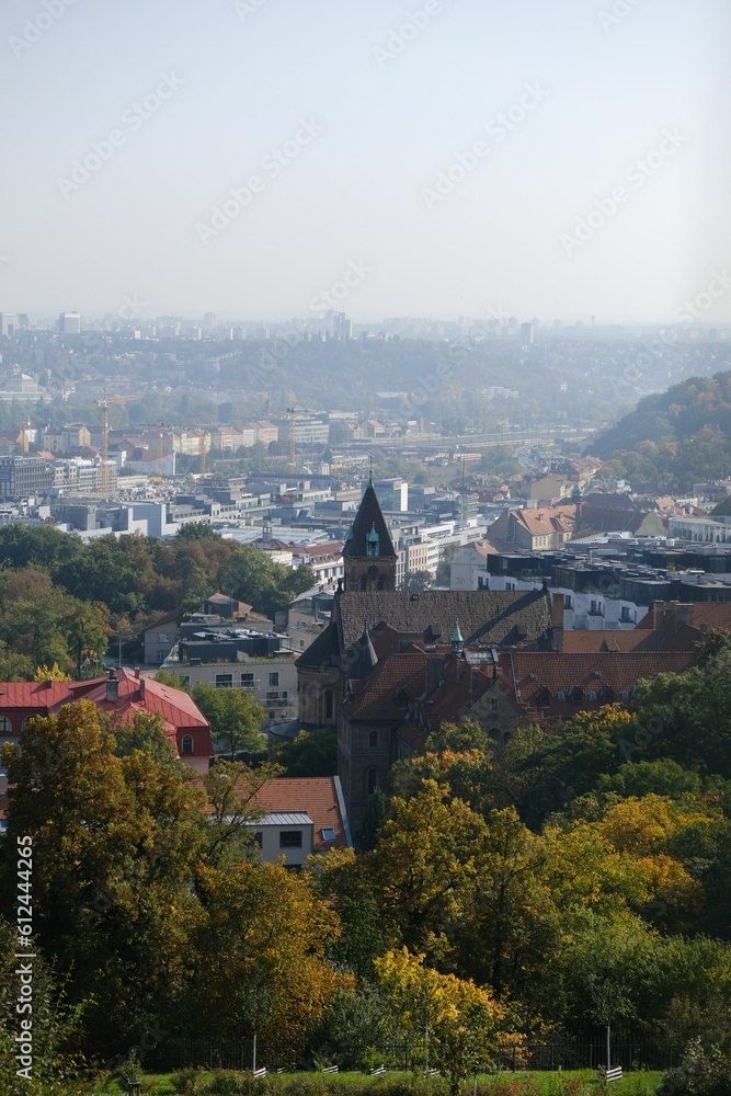 Vertical shot of a church surrounded by lush trees in the Strahov Park in Prague, Czech Republic