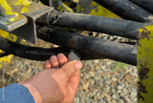Damaged hydraulic line and man's hand pointing at the problem