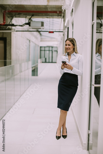 Free Download Young business woman using mobile phone in the office hallway - GFXLoad