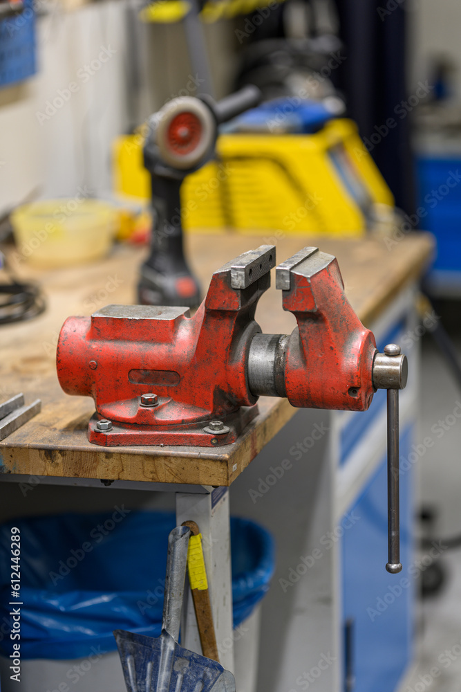A red large hand vise at the table.