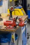 A red large hand vise at the table.