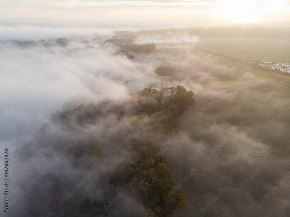 Drone shot of green-covered hills covered with clouds and mist