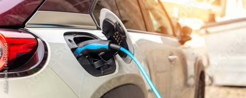 Close-up modern electric plug-in hybrid car parked near fast charger charging station point in center street old European city. Eco friendly green energy vehicle. Zero emission transport technology