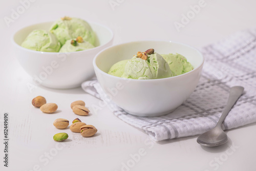 Pistachio homemade Ice cream in a white bowl on a white kitchen table, copy space. Summer cooling desserts